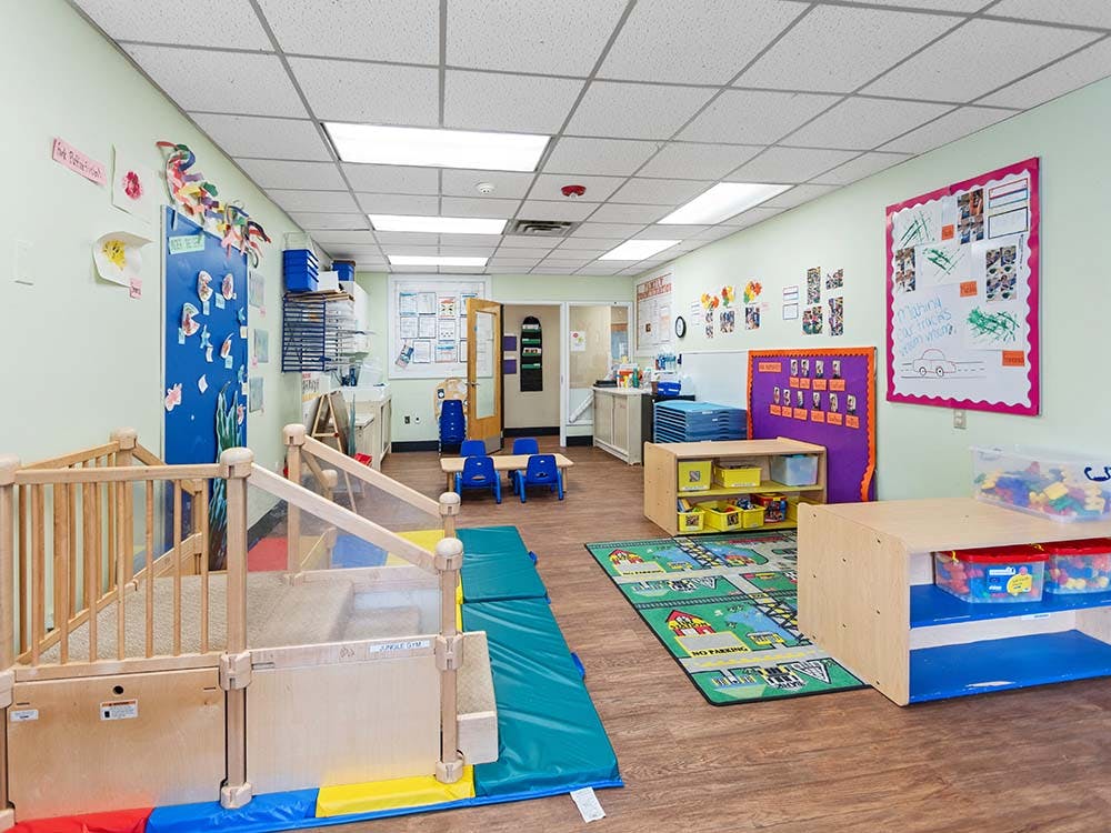 Colorful daycare room with play mats, small tables, and art on the walls