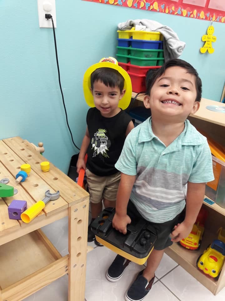 Two children playing with toys, one holding a toolbox