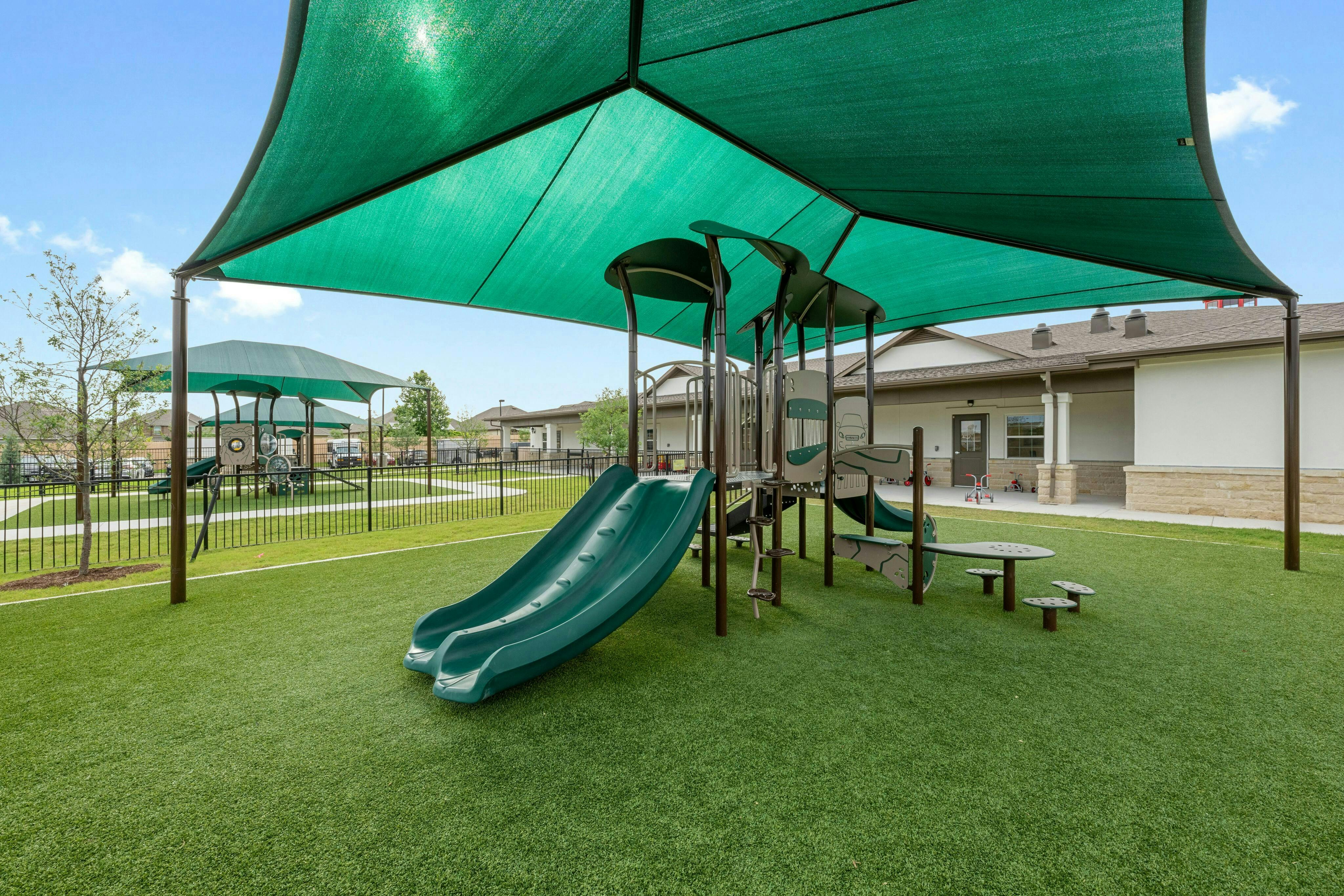 Playground with green slides and a large green shade canopy