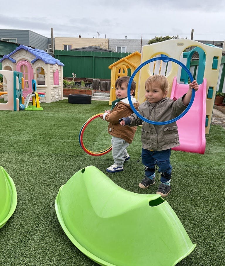 Two children playing with hula hoops in a playground