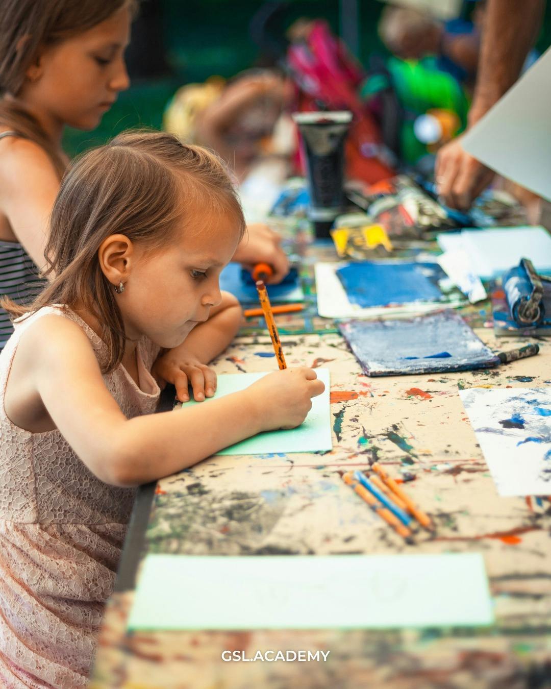 Child drawing on paper with a pencil at a table