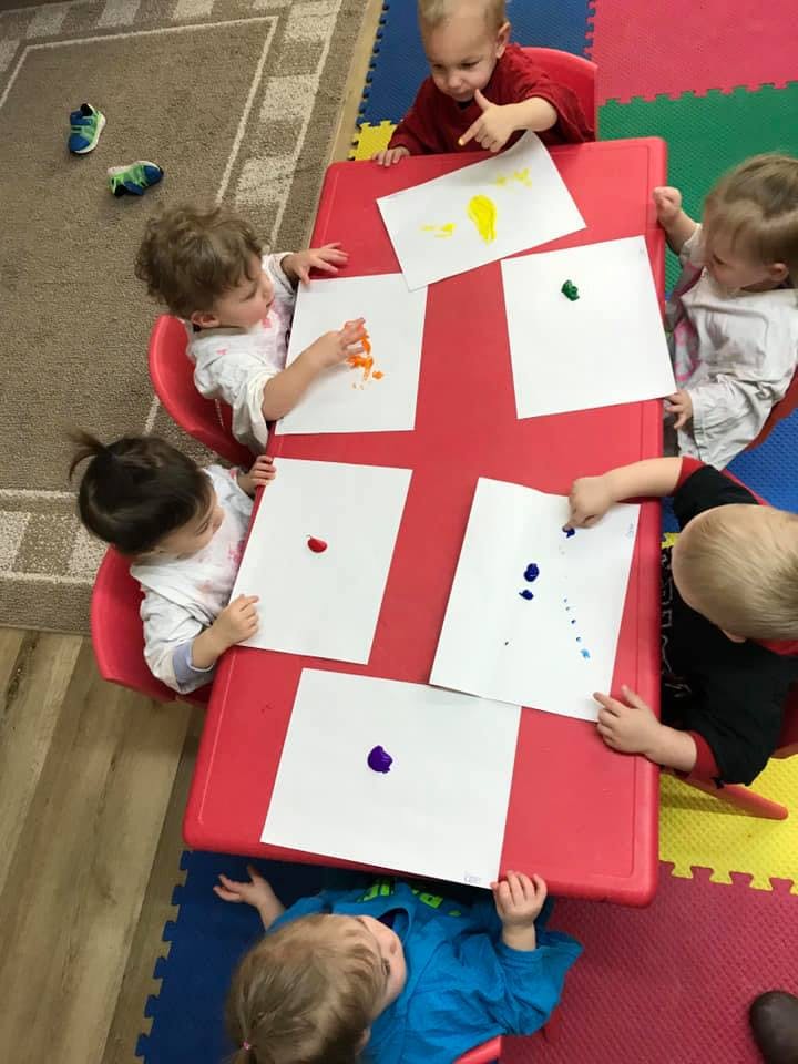Children painting at a red table