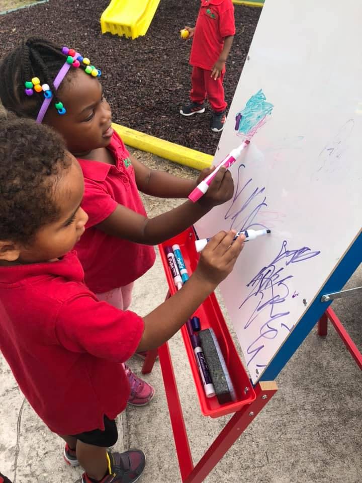 Two children drawing on a whiteboard