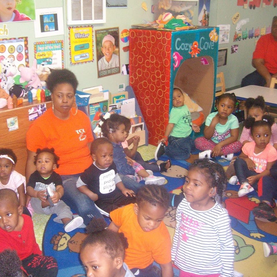 Adult and multiple children sitting on a rug in a classroom