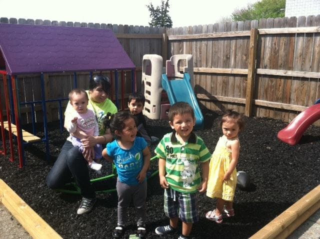 Adult and multiple children on a playground with play structures