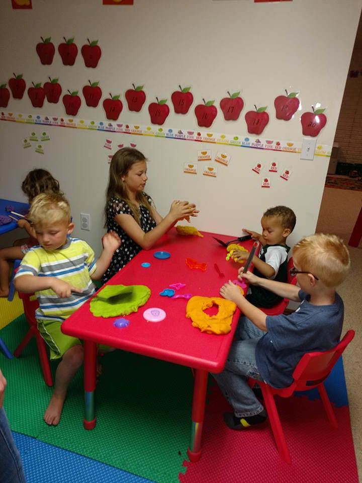 Children playing with modeling clay at a red table