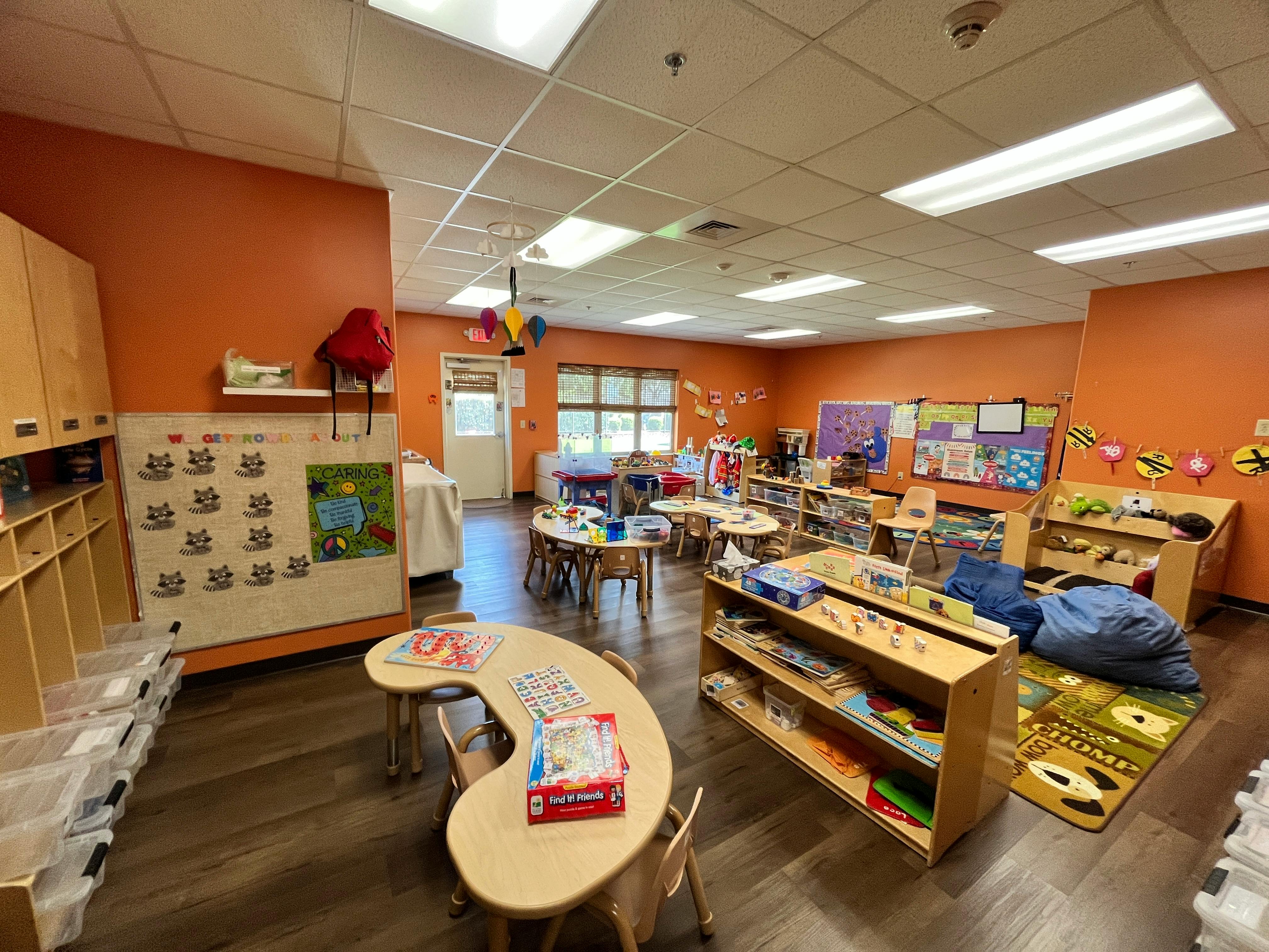 Empty classroom with small tables and chairs, shelves, and wall decorations