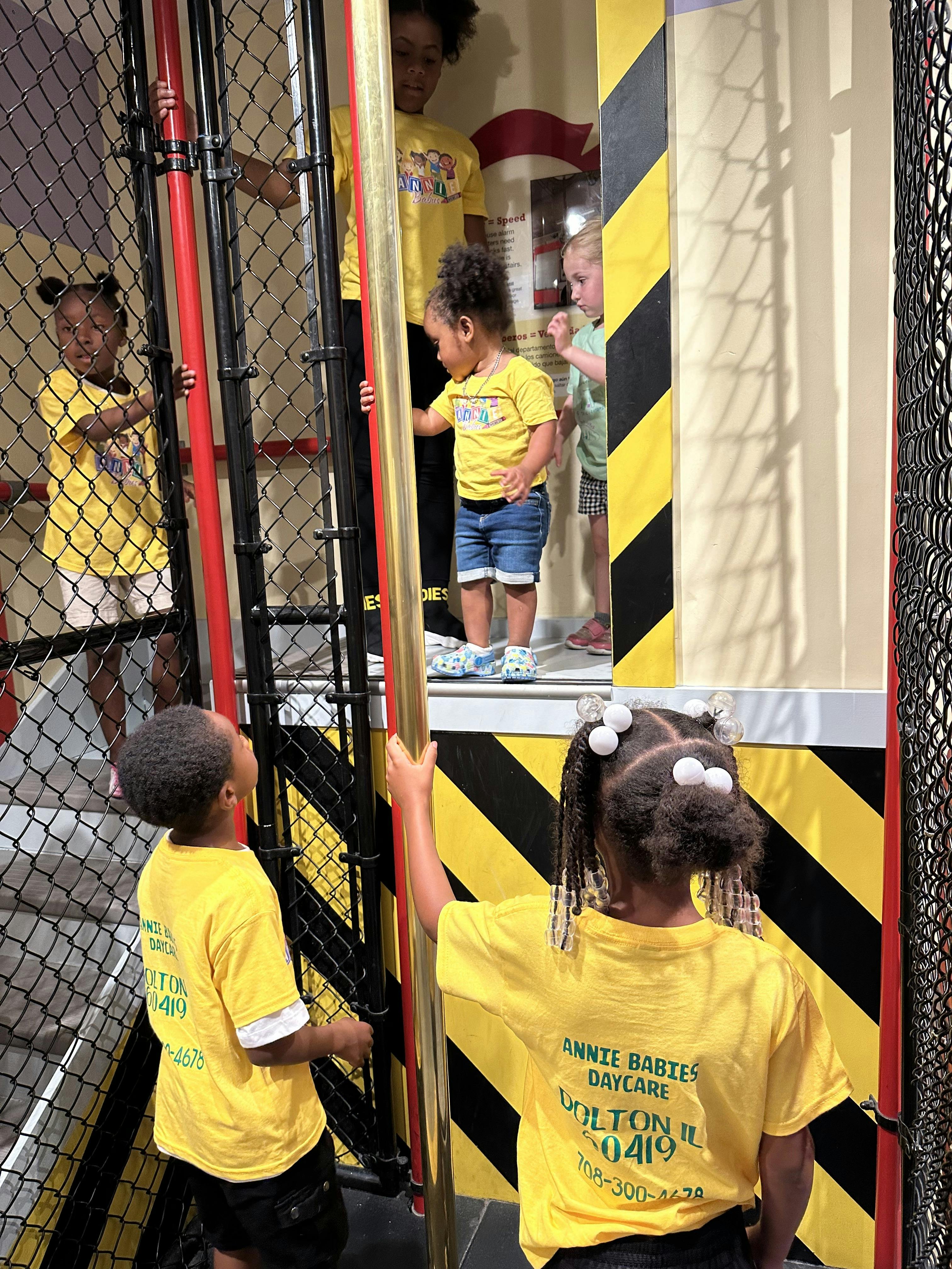 Children in yellow shirts playing on a multi-level structure with fencing