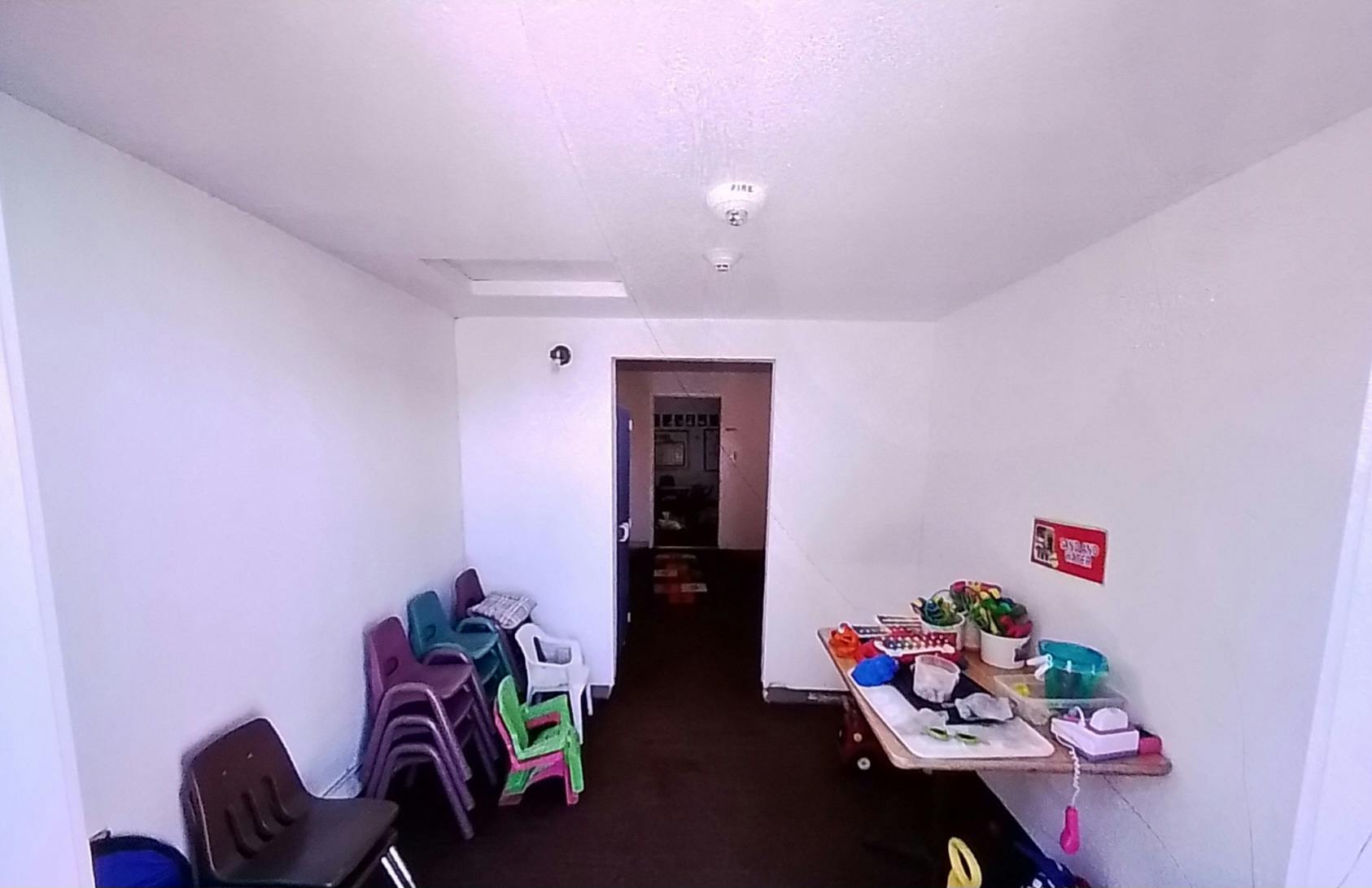 Room with stacked chairs and a table with items, toys and art supplies