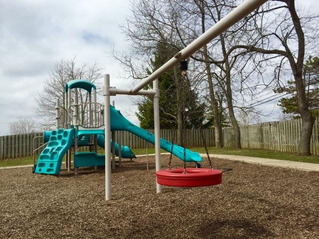 A blue playground structure with slides and a red tire swing on wood chips