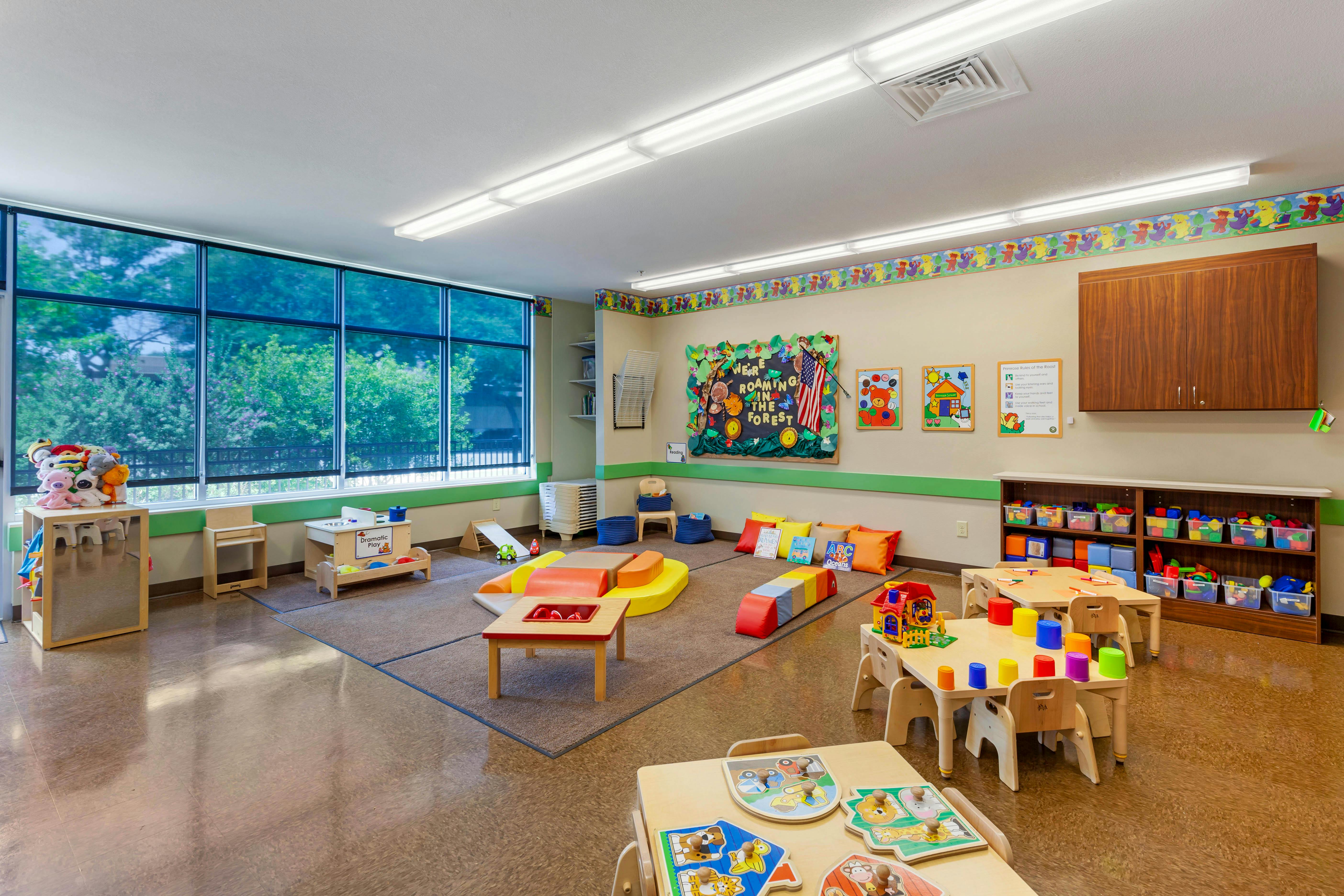 Classroom with child-sized tables, chairs, colorful play equipment, and window