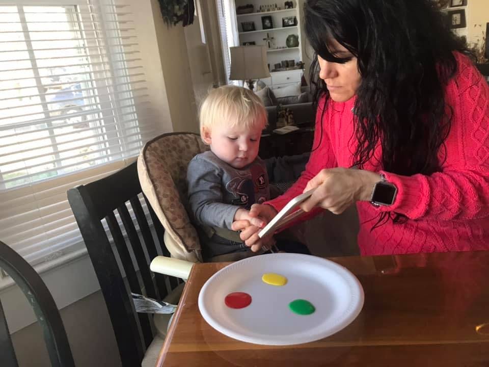Person helping a child with a craft project at a table