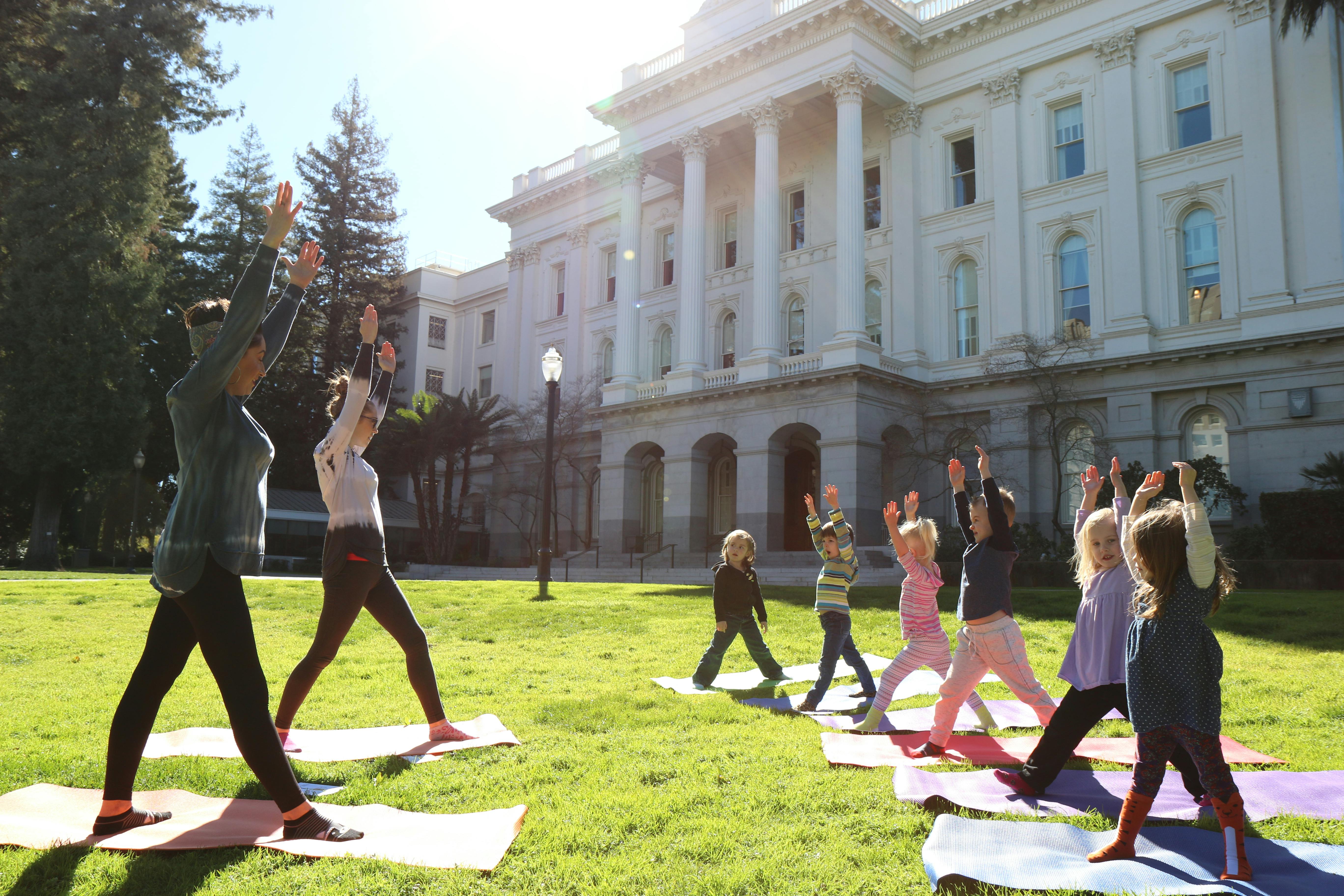 People doing yoga on mats on a lawn in front of a large building