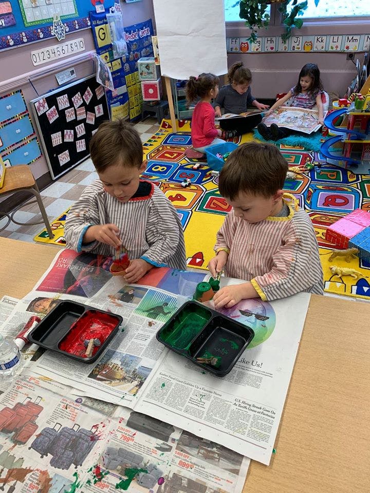 Two children painting at a table in a classroom