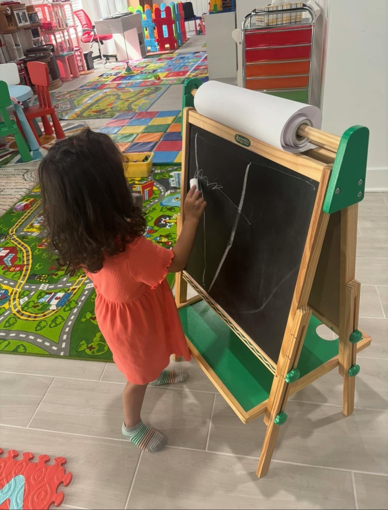 Child drawing on a blackboard with chalk in a playroom