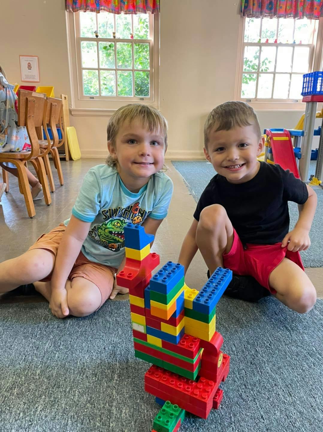 Two children sitting on the floor with a colorful block structure