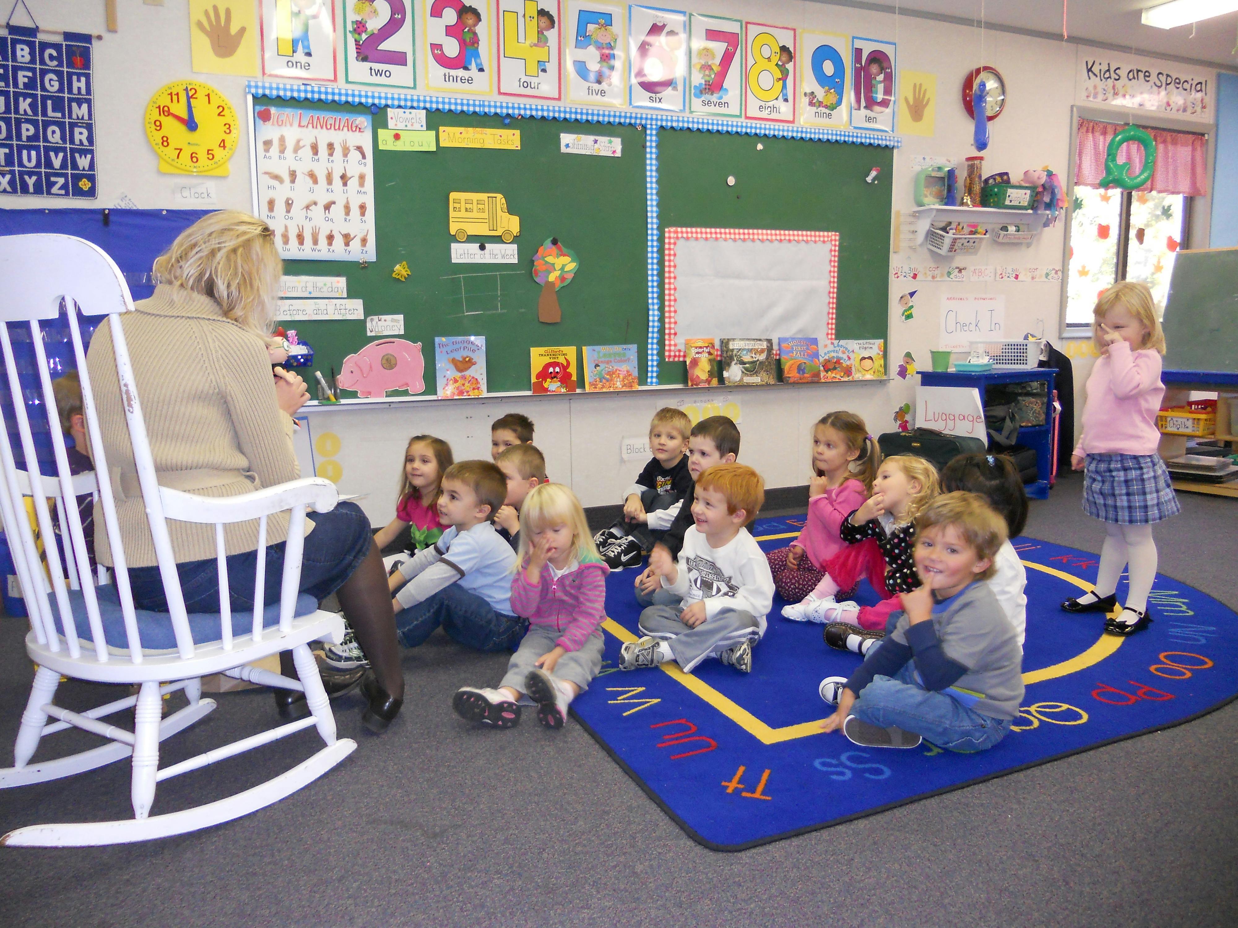 Person in rocking chair reading to children in a classroom