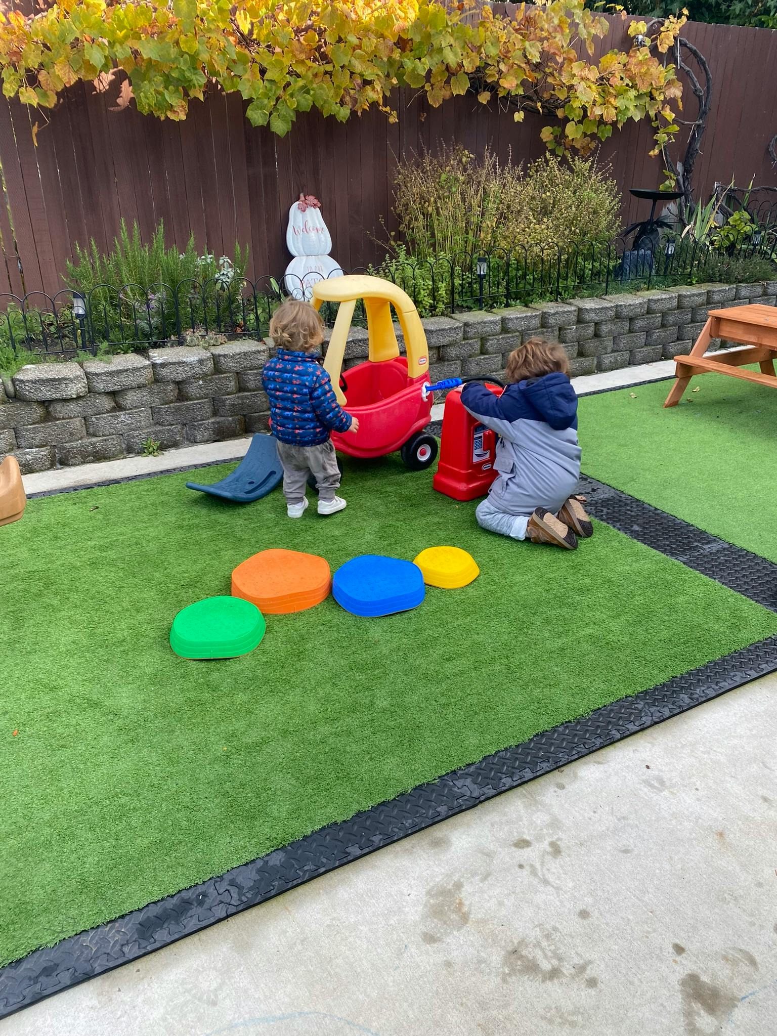 Two children playing with toys on a green turf surface
