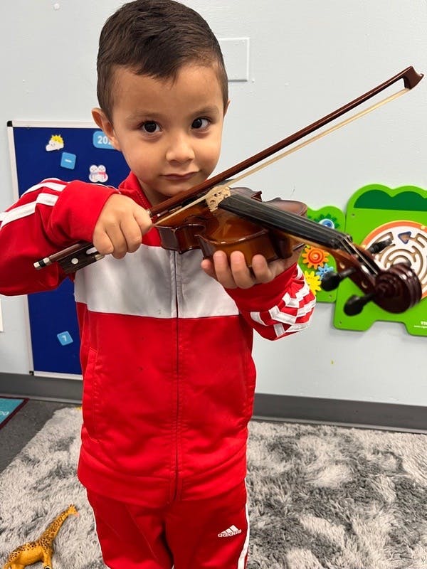 Child holding a violin and bow