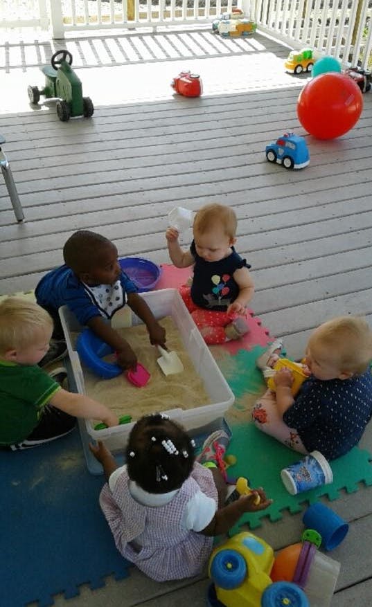 Children playing with sand and toys on a deck