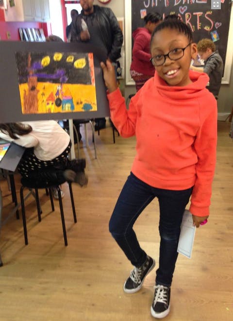 Child in glasses holding up a drawing