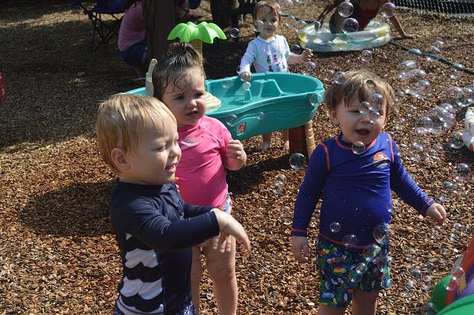 Three children playing with bubbles outdoors