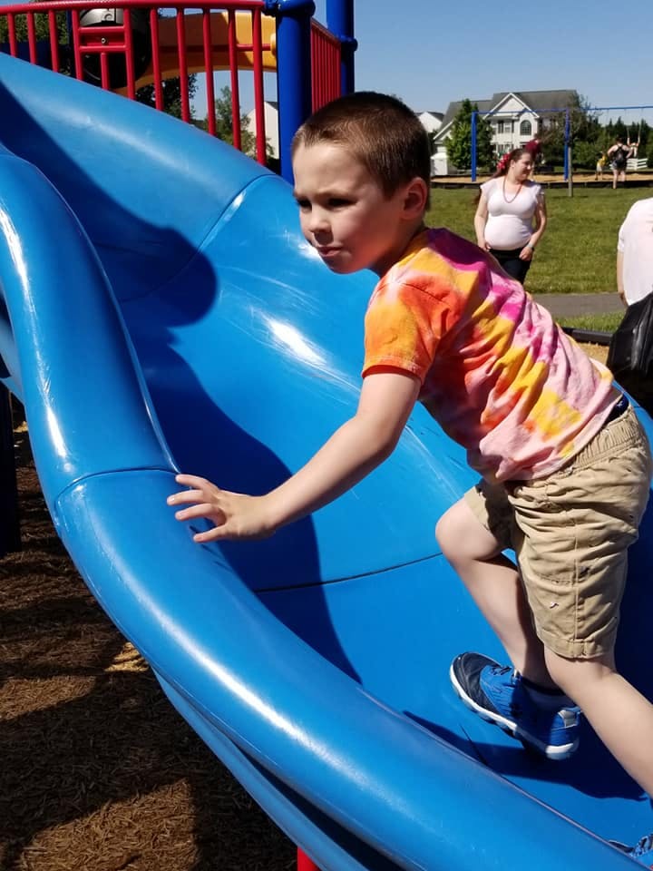 Child climbing up a blue playground slide