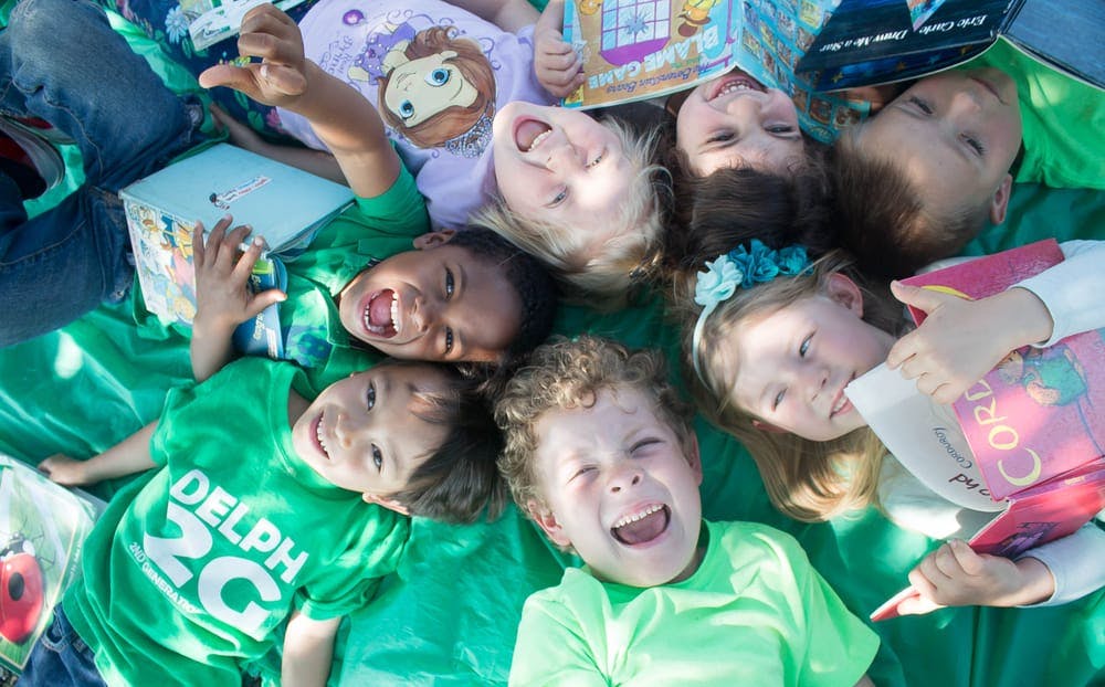 Group of children lying on a green blanket looking up