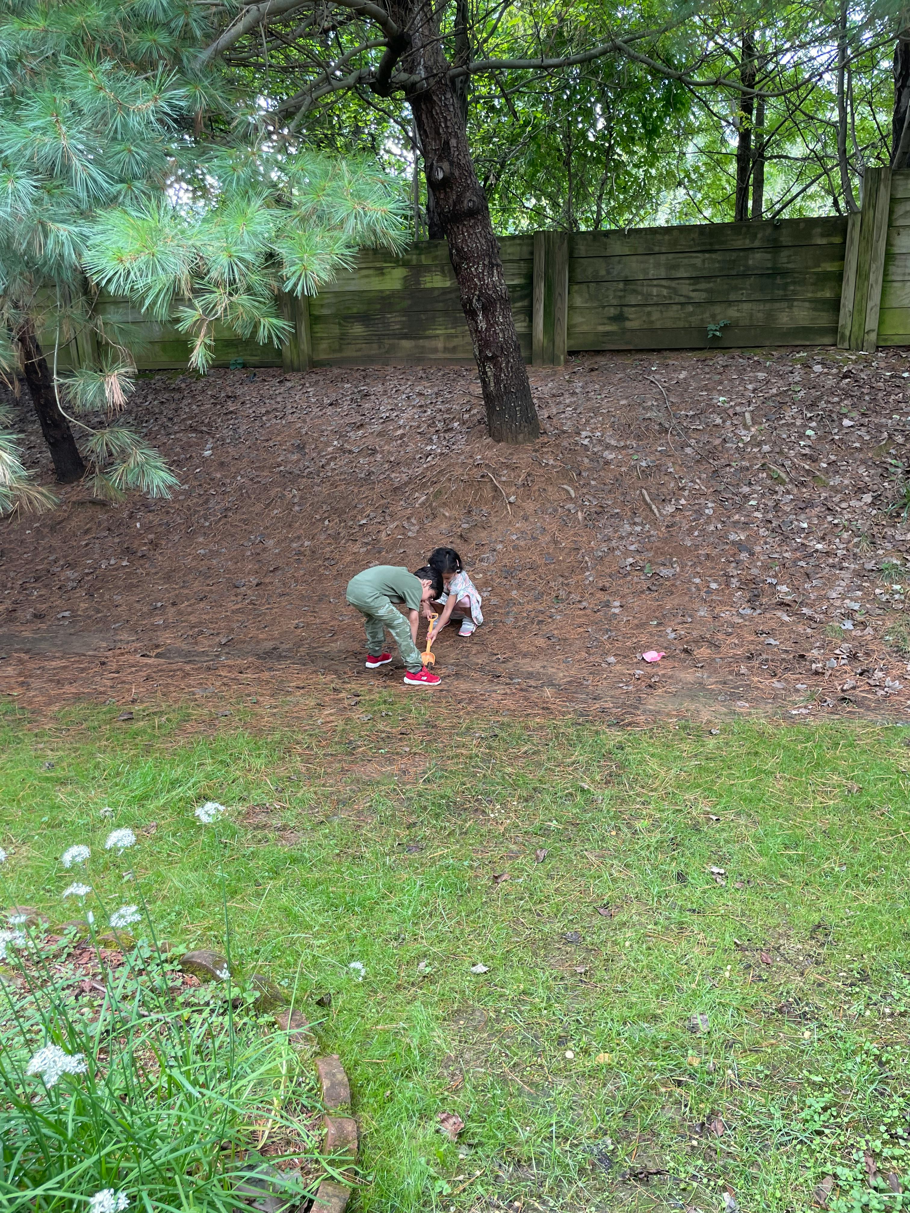 Child bending over next to a dog on a dirt slope