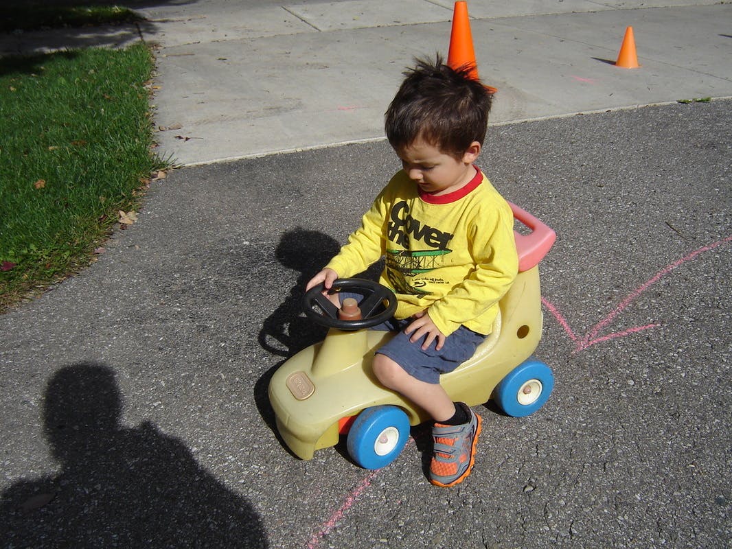 Child sitting on a toy car on pavement