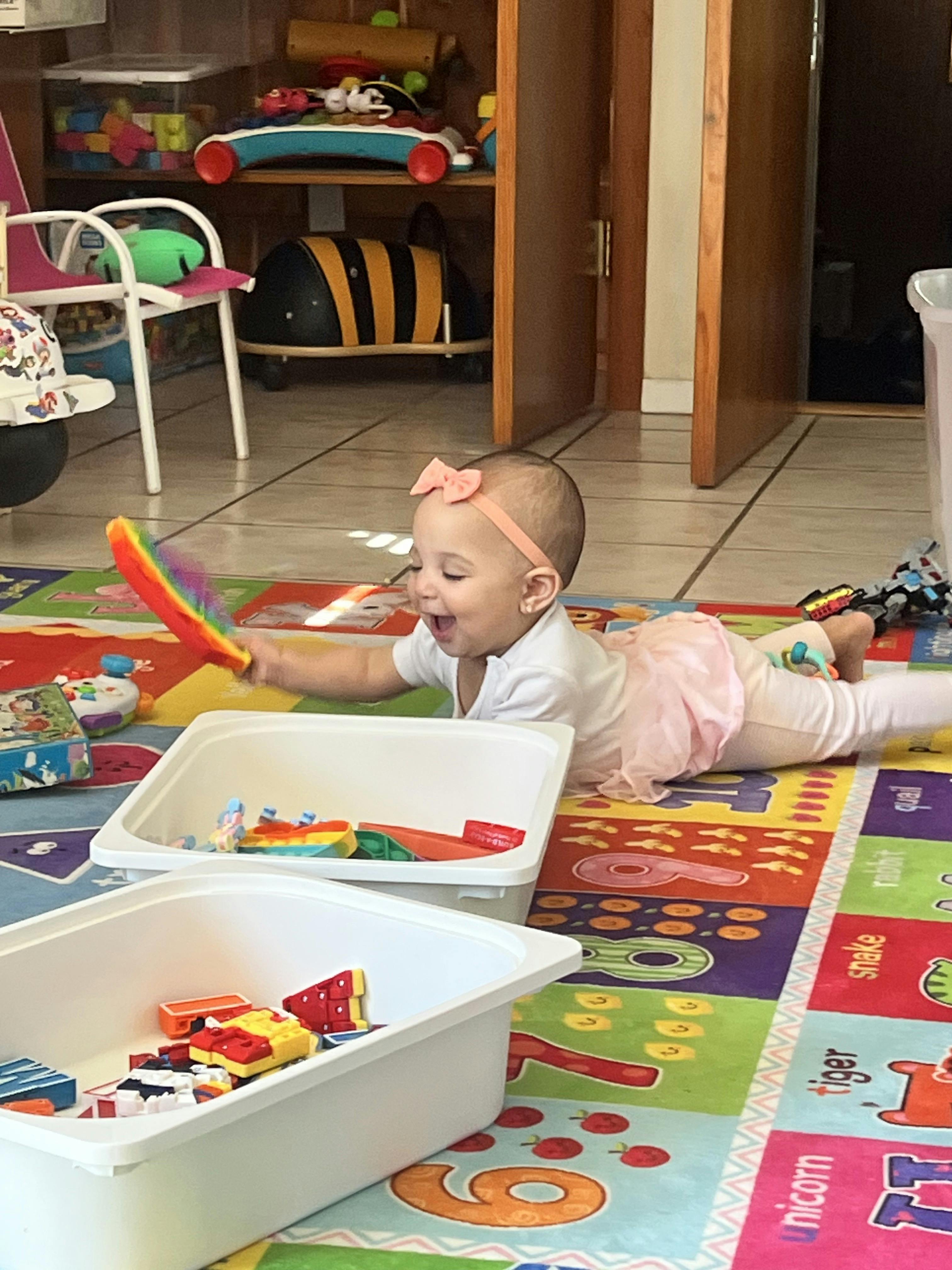 Child playing with toys on a colorful mat
