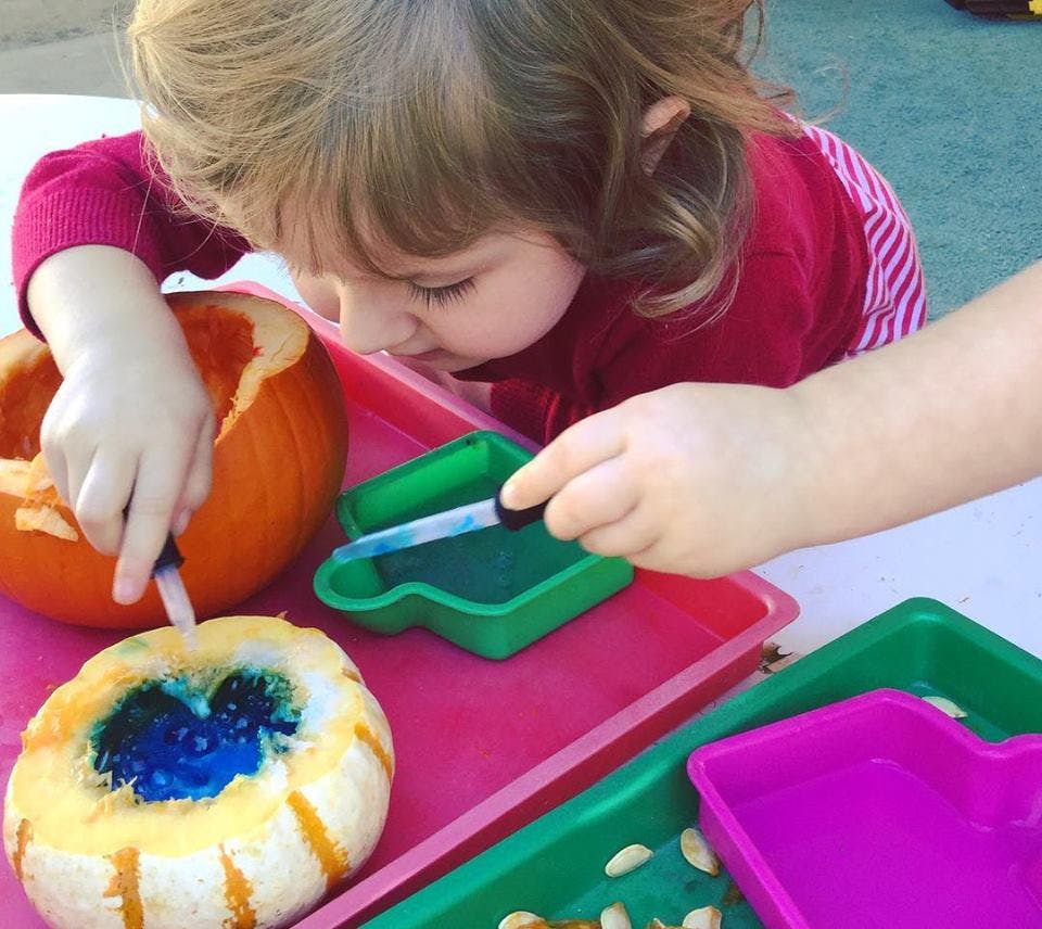 Child using a dropper to add liquid to a pumpkin