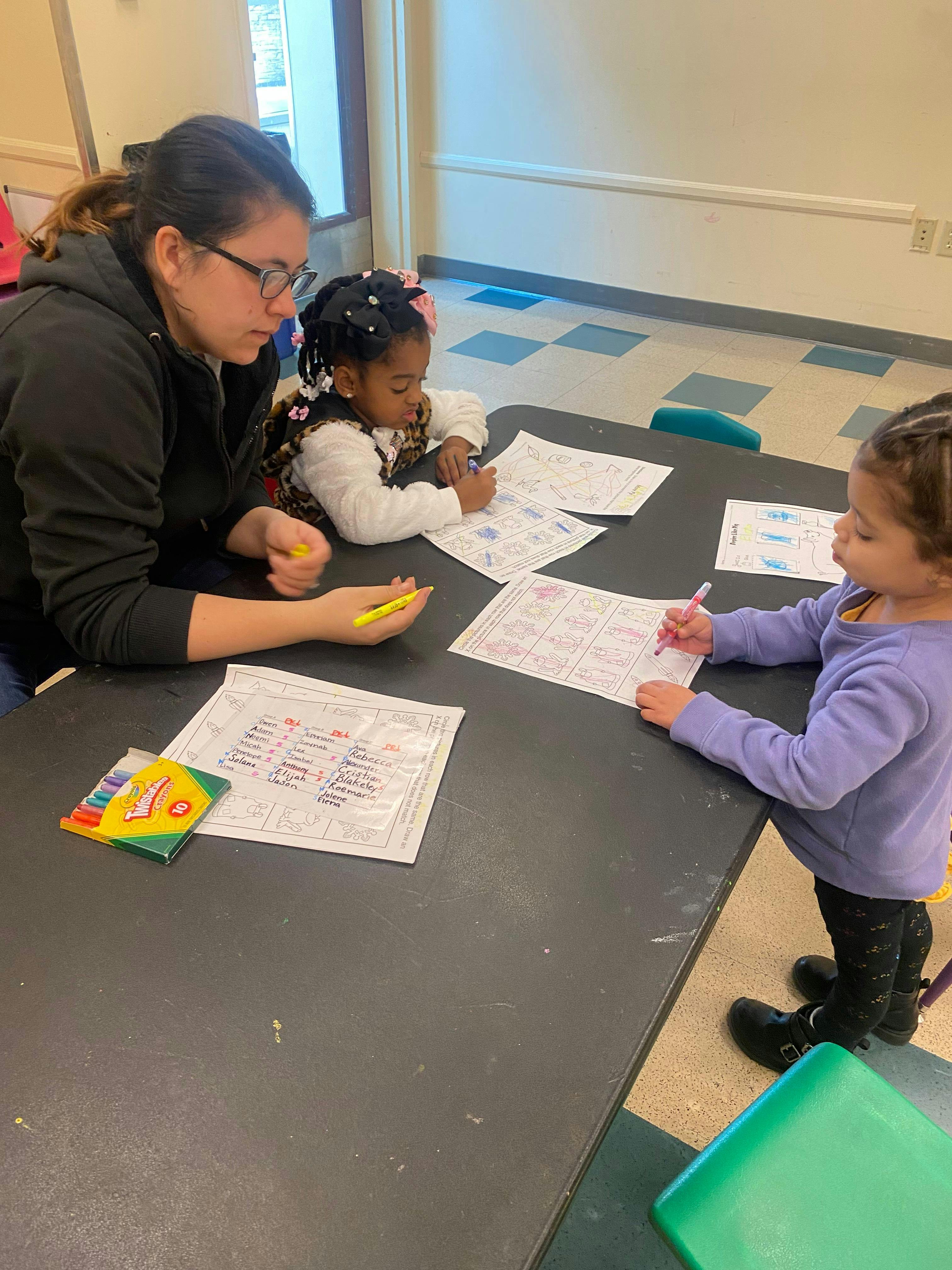 Person and two children drawing at a table