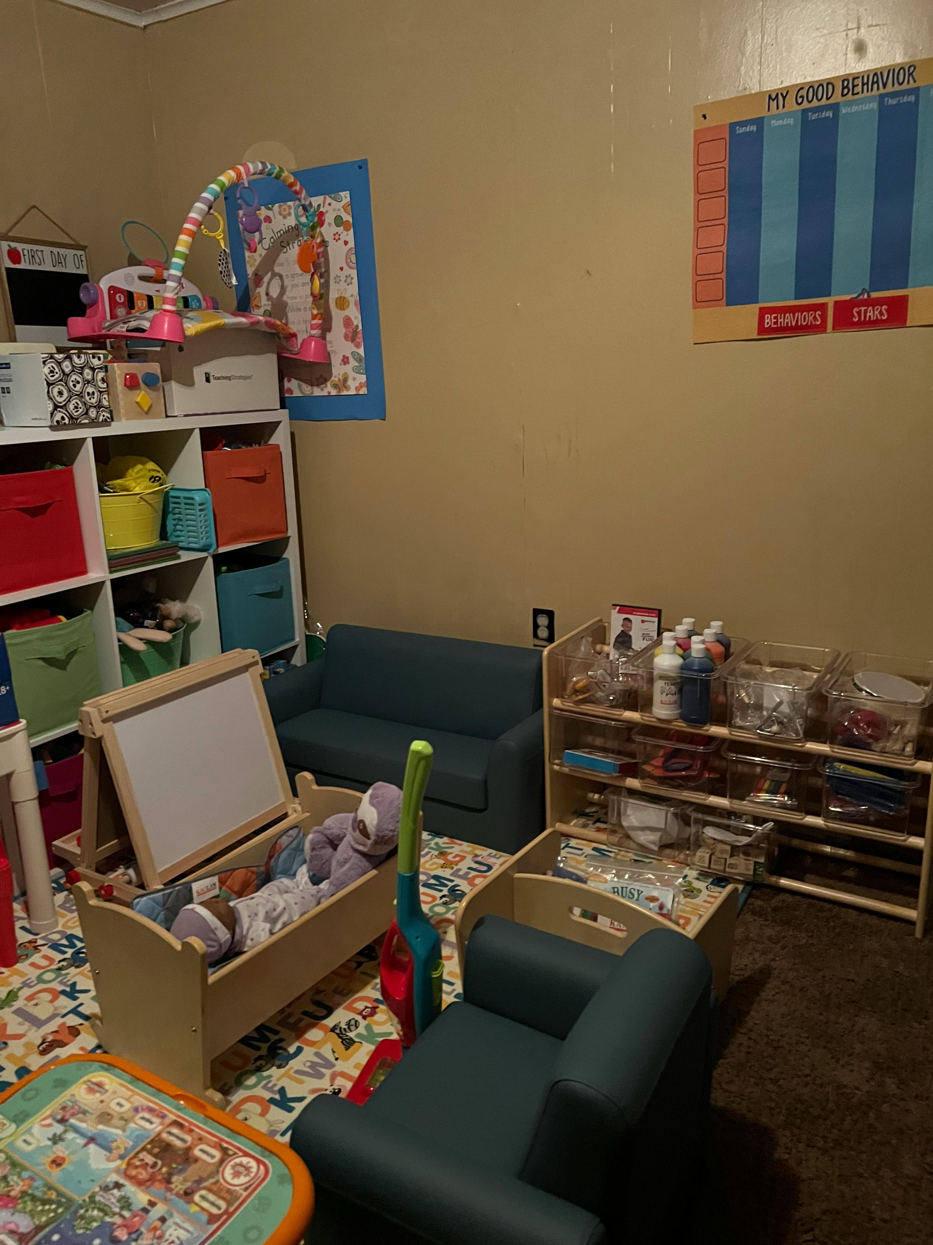 Playroom with a small blue couch, shelves with toys, and a behavior chart on the wall