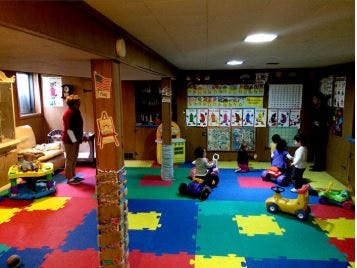 Children playing on ride-on toys in a room with colorful floor mats