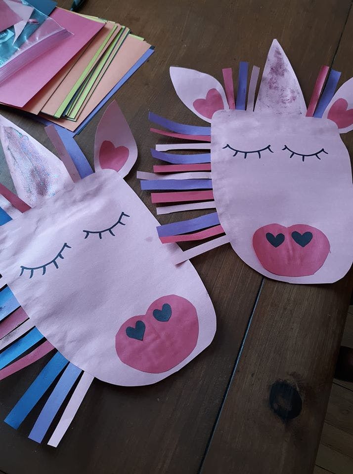 Two paper unicorn crafts with closed eyes and heart-shaped noses