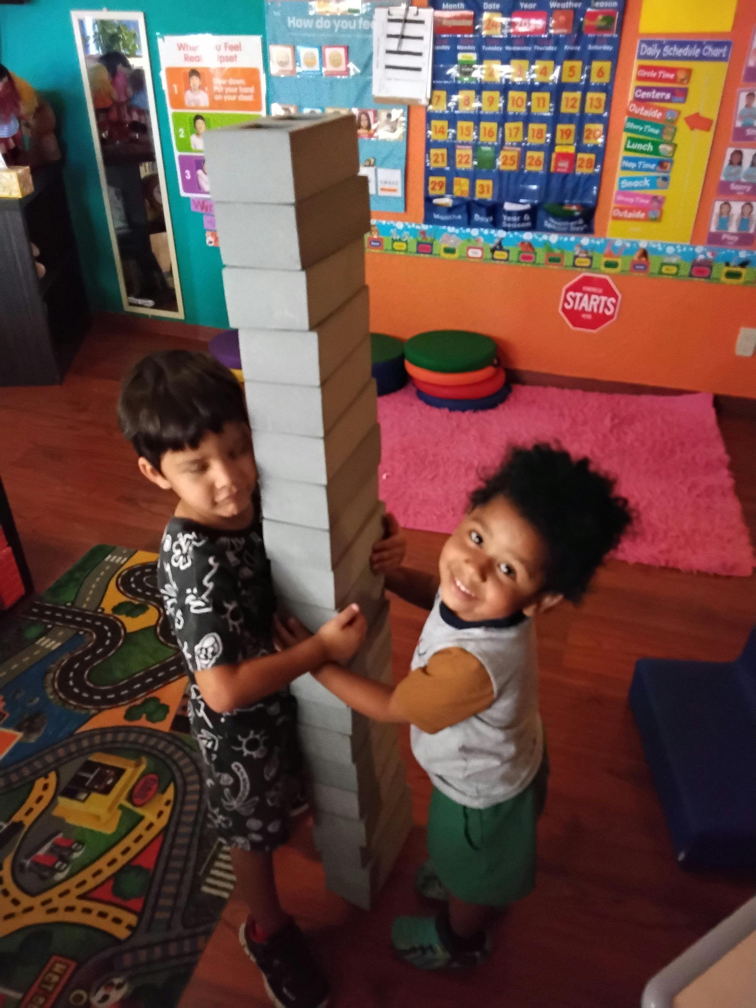 Two children playing with large foam blocks on the floor