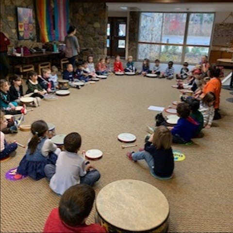 Children sitting in a circle on the floor with drums