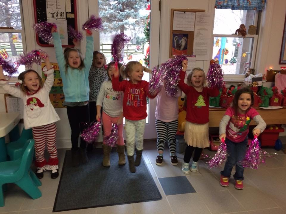 Group of children jumping with pom-poms in a classroom