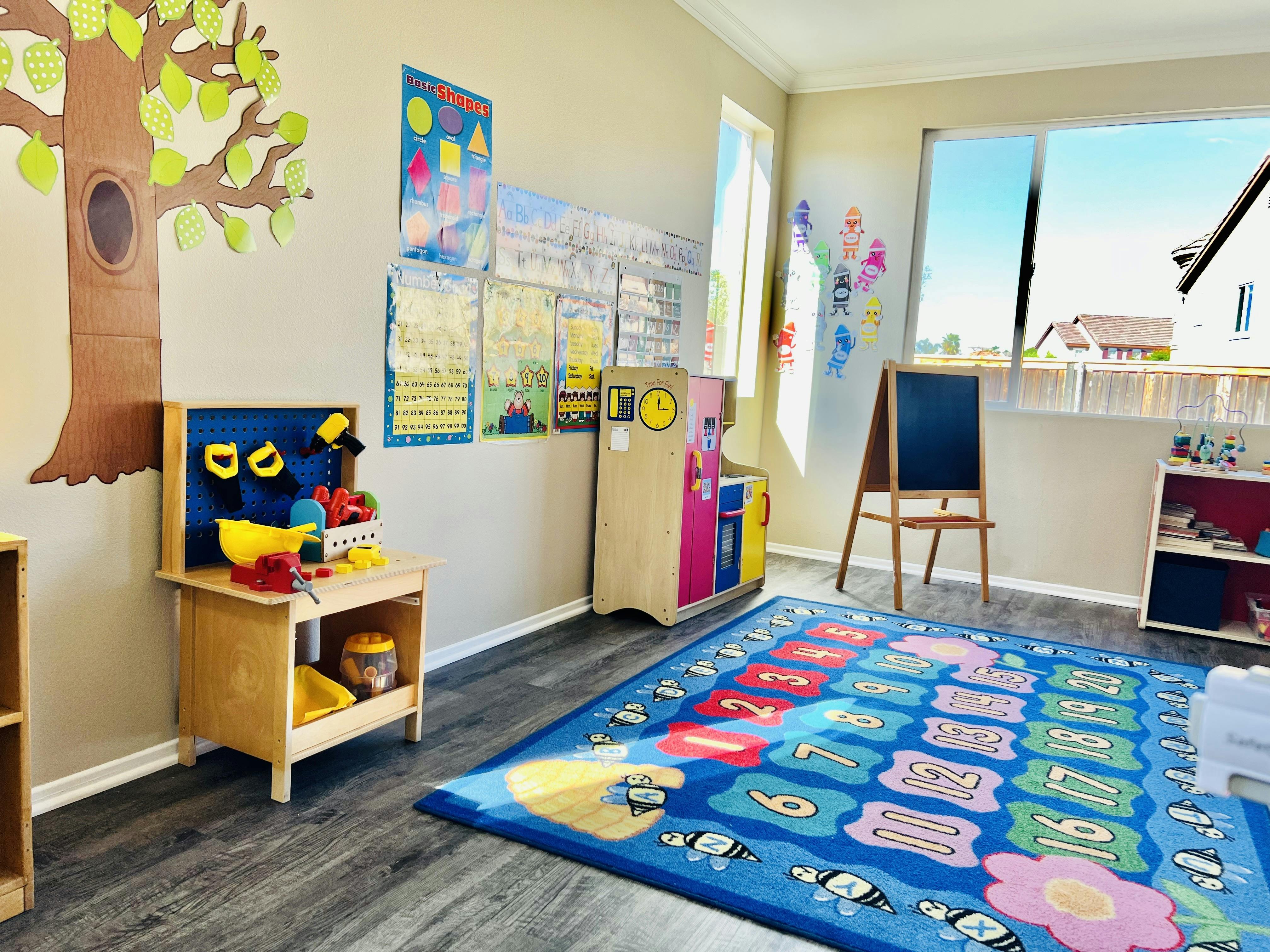 Children's playroom with a play workbench, colorful rug, chalkboard, and educational posters