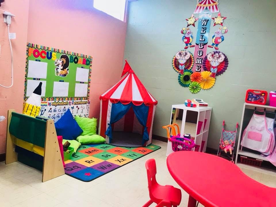 Playroom with a red and white striped tent, colorful rug, and bulletin board
