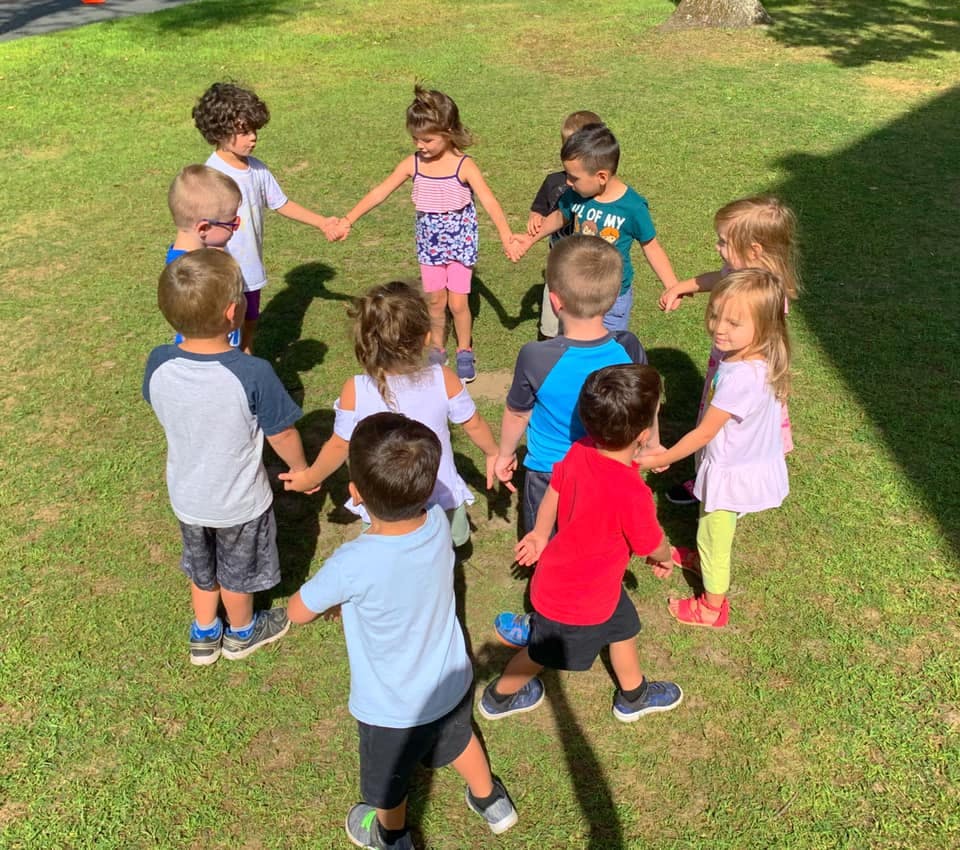 Children holding hands in a circle on grass