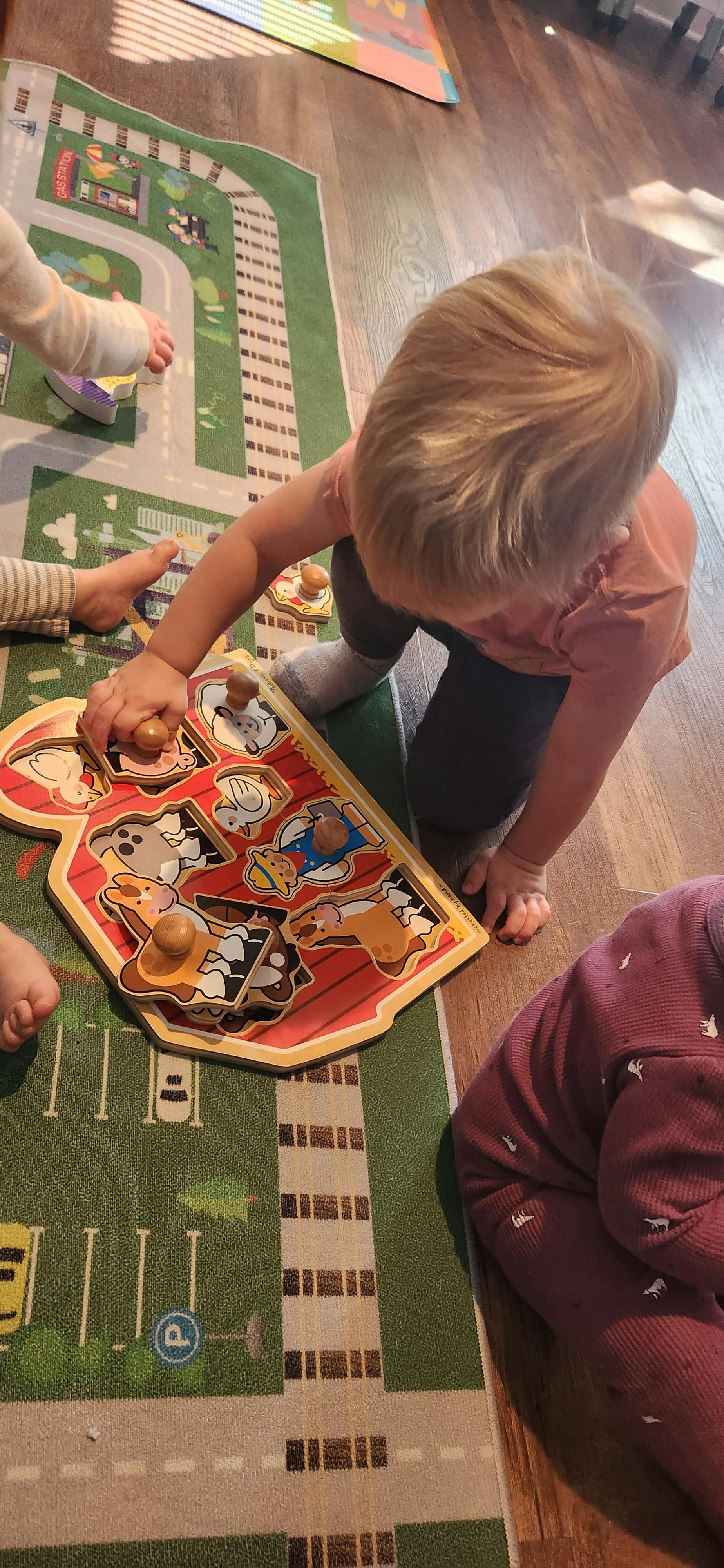 Child playing with a farm animal puzzle on a playmat