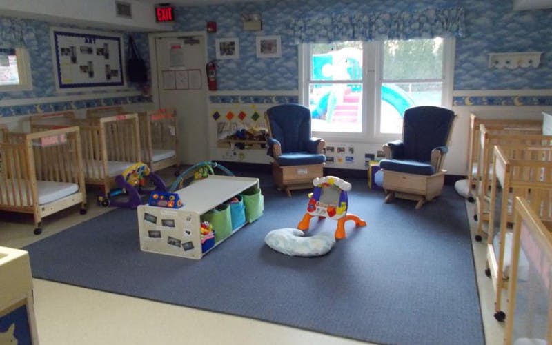 daycare room with cribs, rocking chairs, and play mats