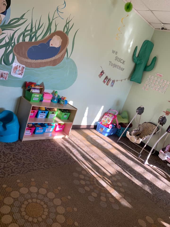 Nursery room with a baby mural, toy shelf, and baby swings