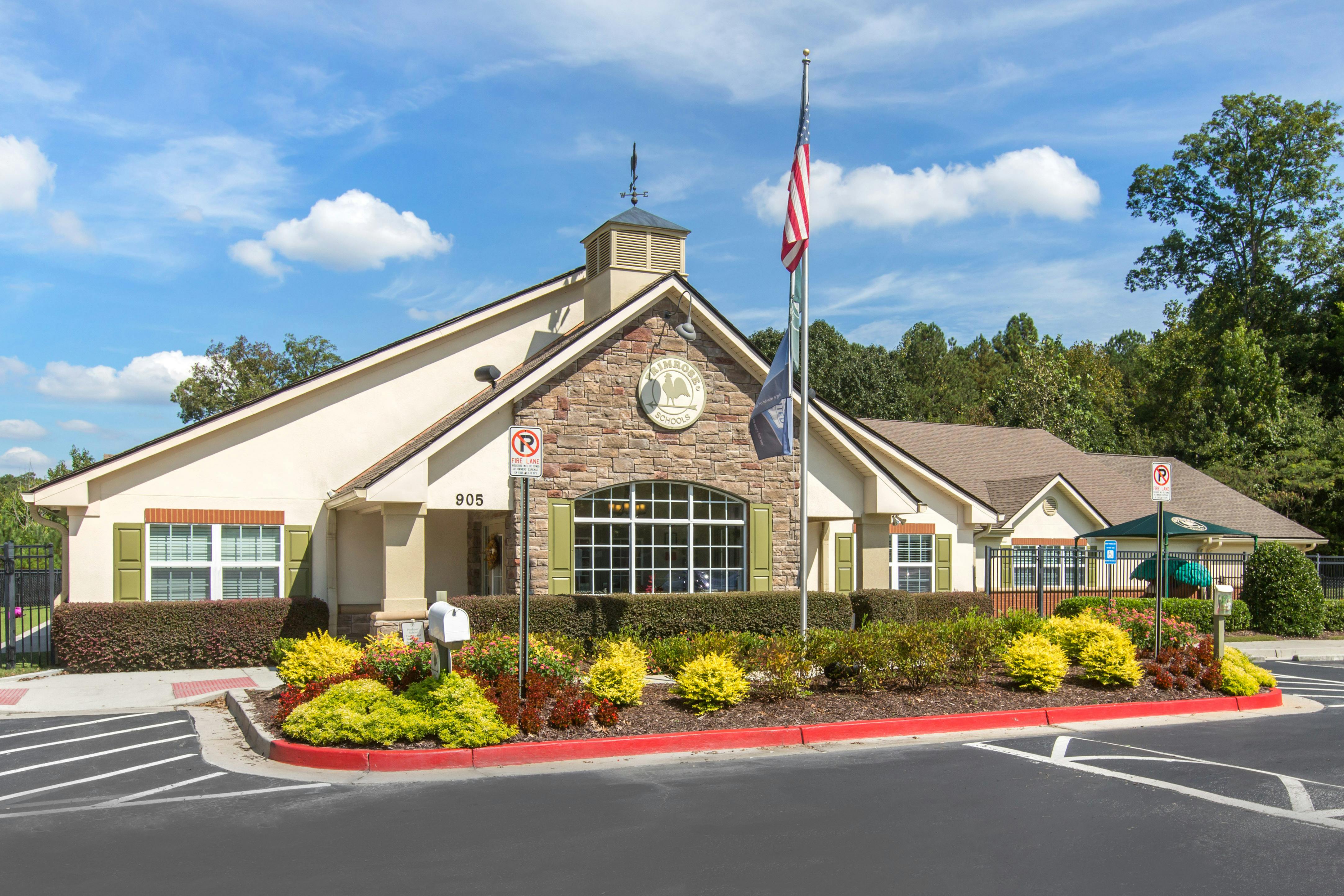 Front exterior of a Primrose Schools building with stone and stucco, a flagpole, and landscaping