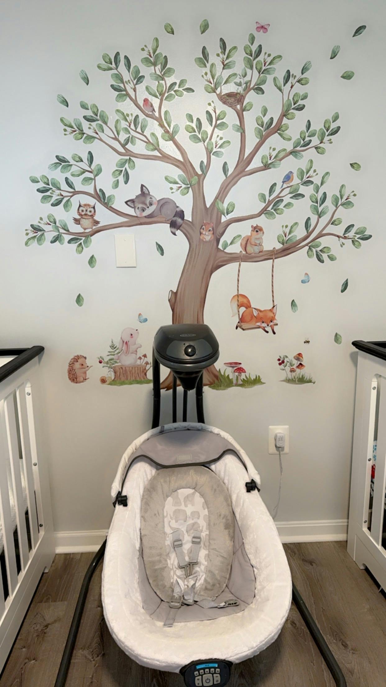 Baby swing in a room with a tree and animal wall decal