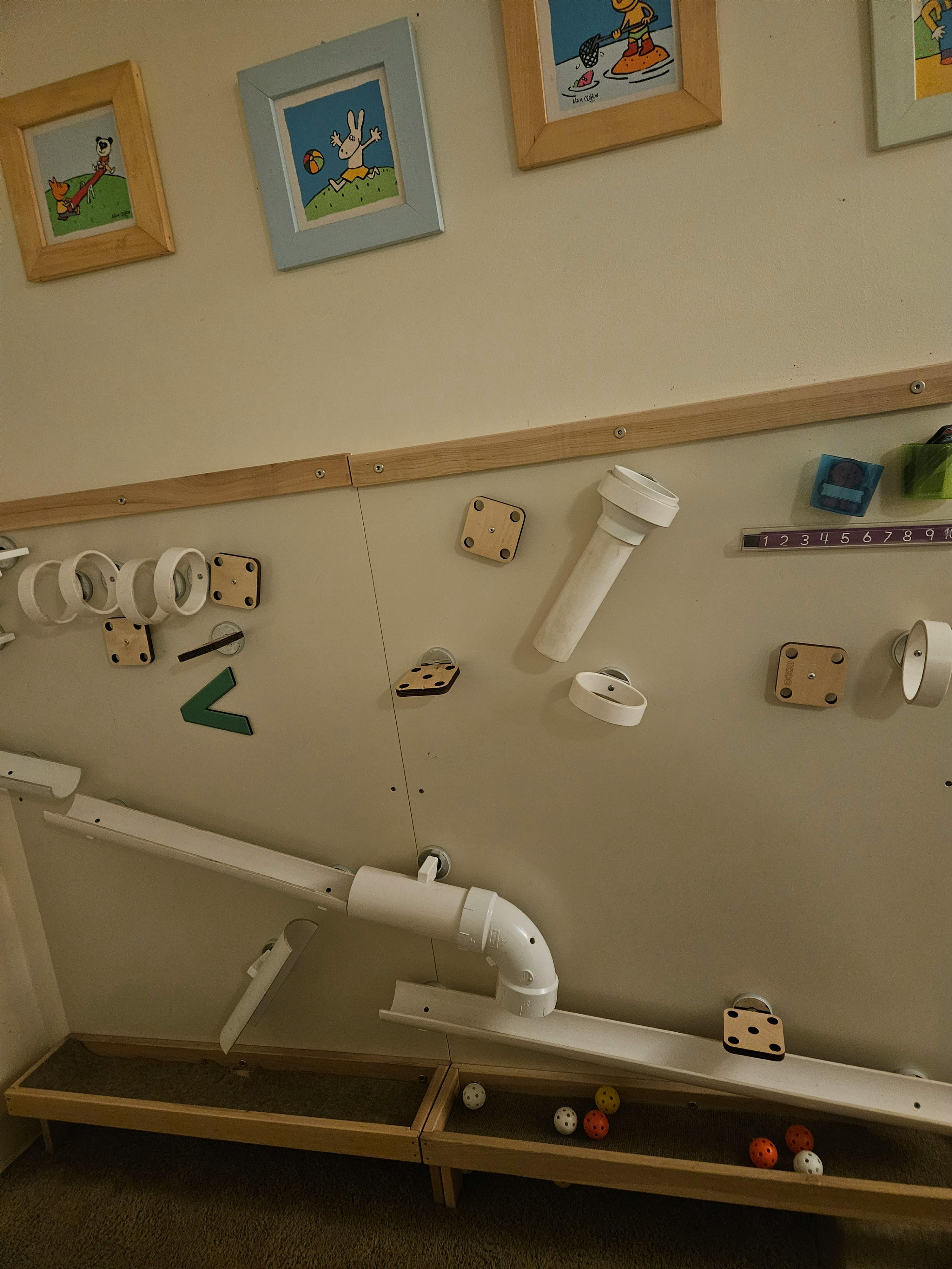 Wall-mounted marble run toy with plastic pipes and tracks