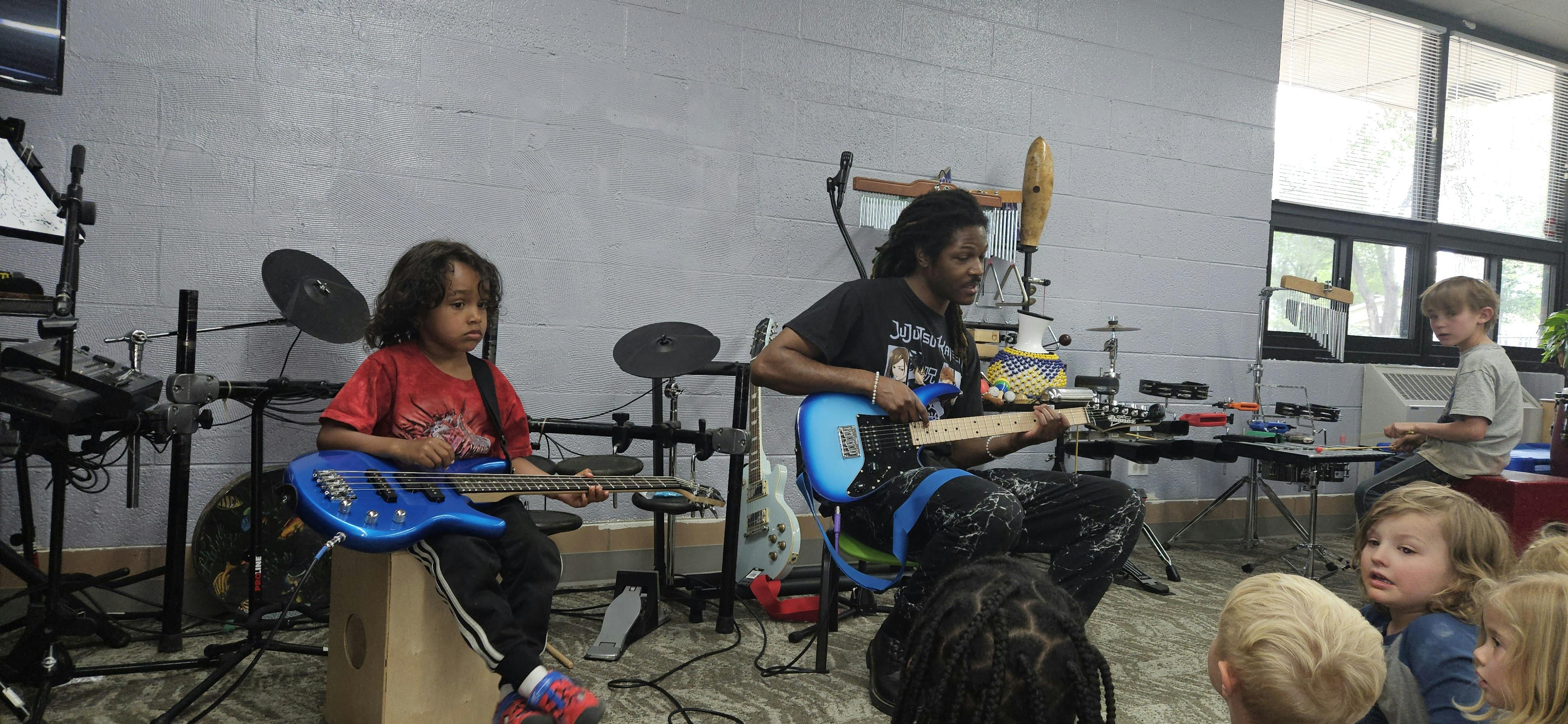 Child and person playing electric guitars