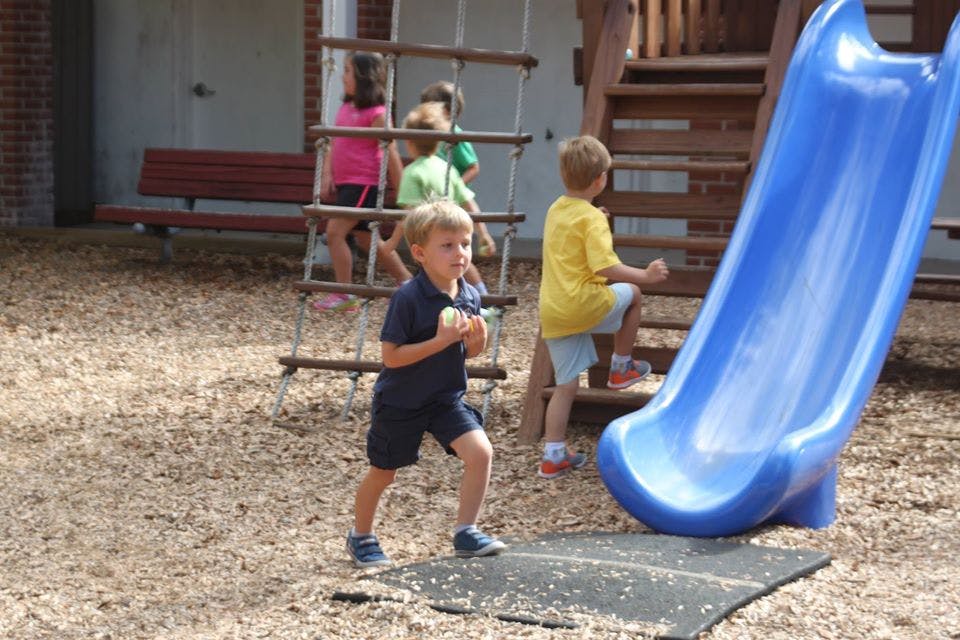 Children playing on a playground with a slide and climbing structure
